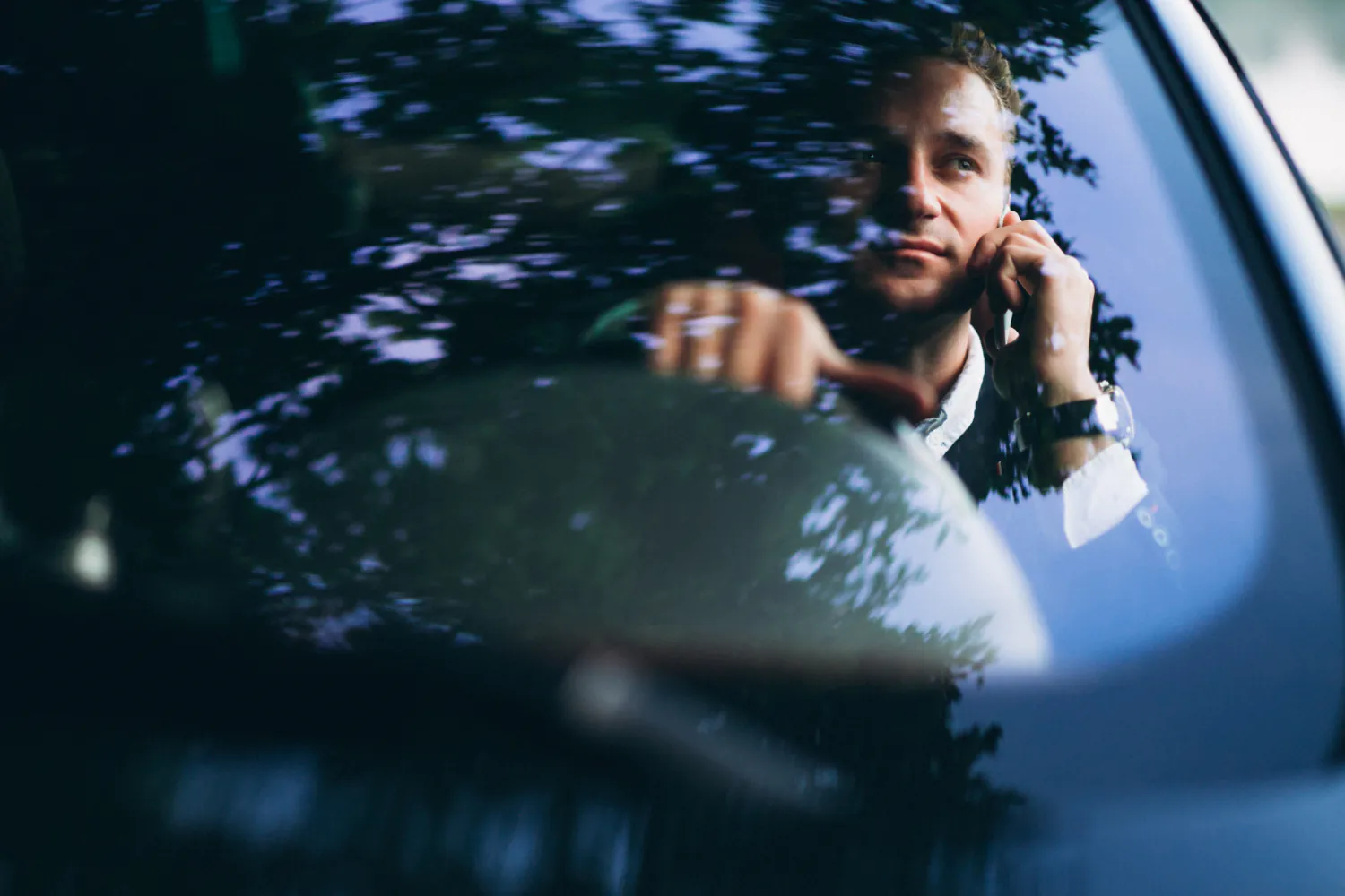 homem falando ao telefone dentro do carro dirigindo